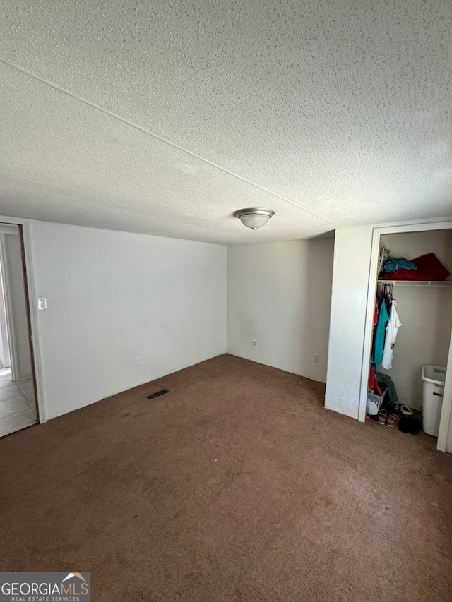 unfurnished room with carpet and a textured ceiling