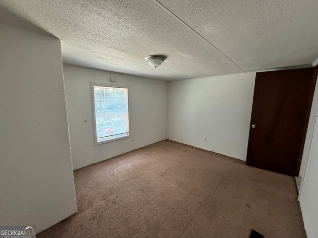 unfurnished room with light colored carpet and a textured ceiling