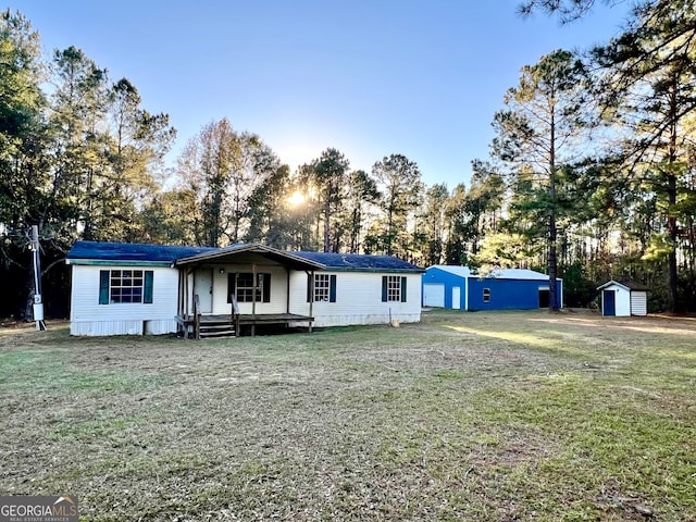 view of front of home with a front yard, a storage shed, and covered porch