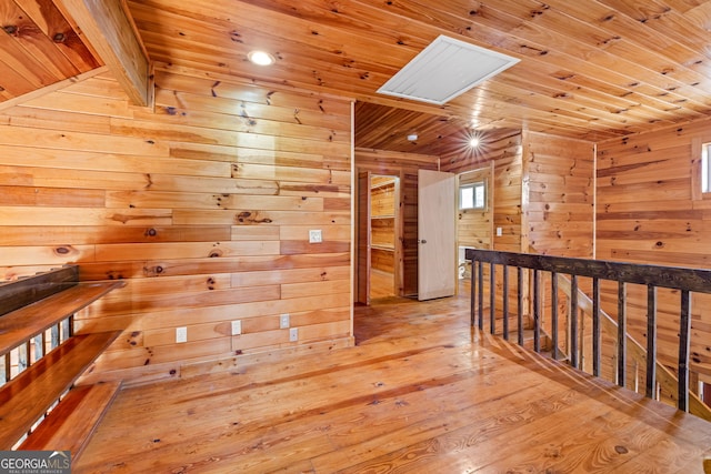 corridor with a skylight, light hardwood / wood-style flooring, wooden ceiling, and wood walls