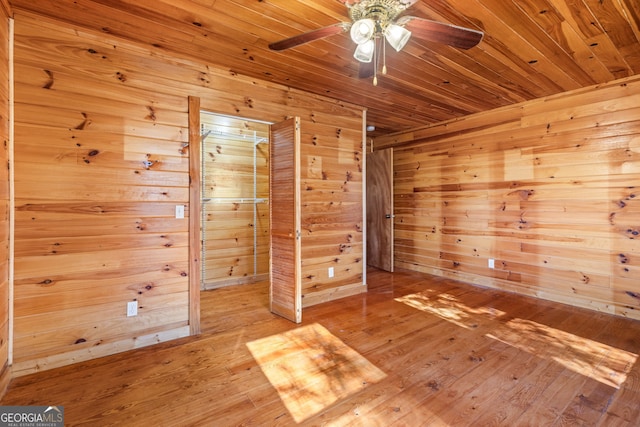 spare room featuring ceiling fan, hardwood / wood-style flooring, wood ceiling, and wood walls