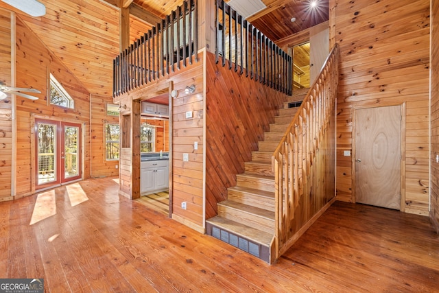 staircase featuring wooden walls, hardwood / wood-style floors, high vaulted ceiling, and wood ceiling