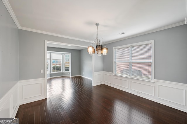 spare room featuring dark hardwood / wood-style floors, ornamental molding, and a notable chandelier