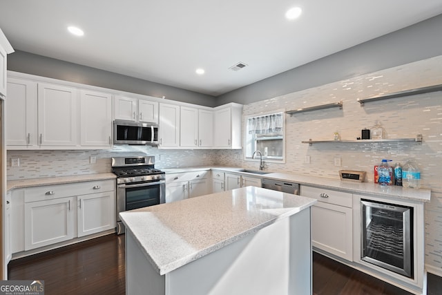 kitchen featuring white cabinetry, light stone counters, beverage cooler, and appliances with stainless steel finishes