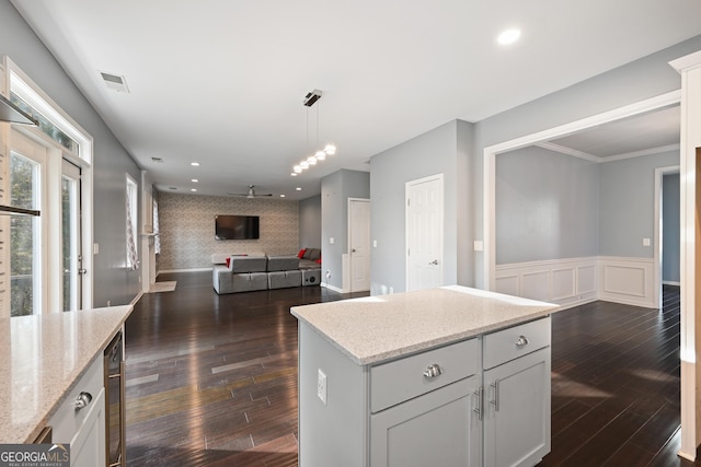 kitchen featuring dark hardwood / wood-style flooring, wine cooler, hanging light fixtures, light stone countertops, and a center island