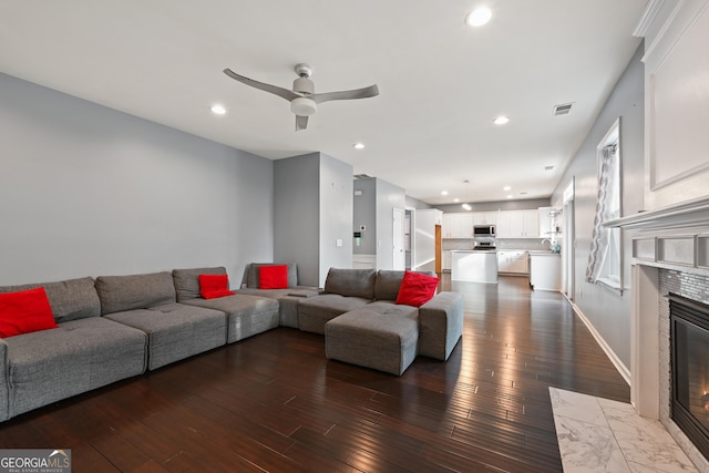 living room featuring ceiling fan, wood-type flooring, and a fireplace