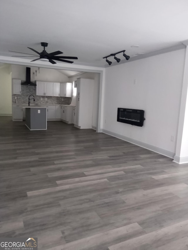 unfurnished living room with heating unit, dark hardwood / wood-style floors, ceiling fan, and sink