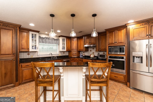 kitchen with pendant lighting, backsplash, appliances with stainless steel finishes, a kitchen island, and a kitchen bar