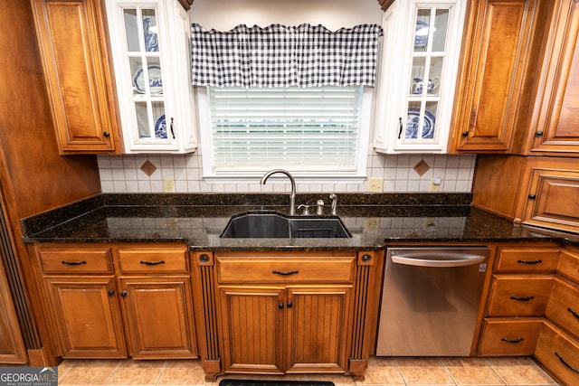 kitchen featuring stainless steel dishwasher, decorative backsplash, dark stone countertops, and sink