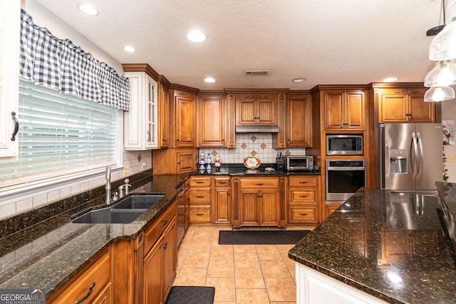 kitchen featuring decorative backsplash, a textured ceiling, stainless steel appliances, sink, and pendant lighting