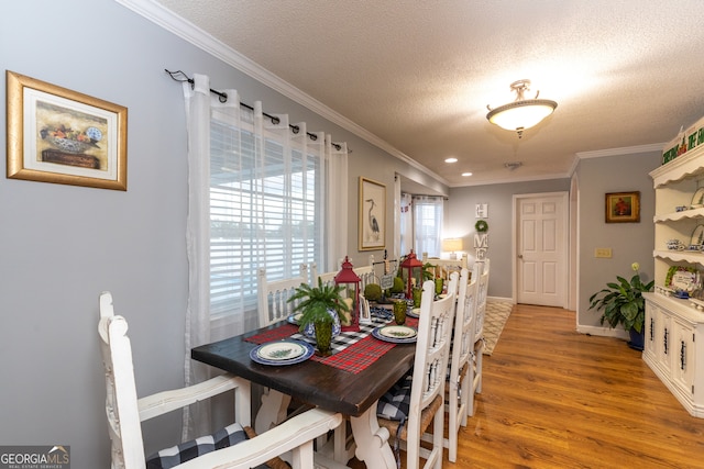 dining space with light hardwood / wood-style flooring, a textured ceiling, and ornamental molding