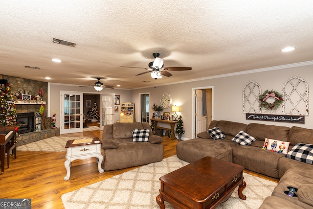 living room featuring a textured ceiling, light wood-type flooring, and a stone fireplace