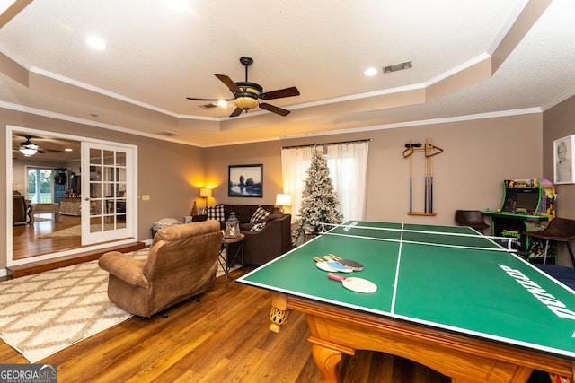 playroom with hardwood / wood-style flooring, ceiling fan, a raised ceiling, and crown molding