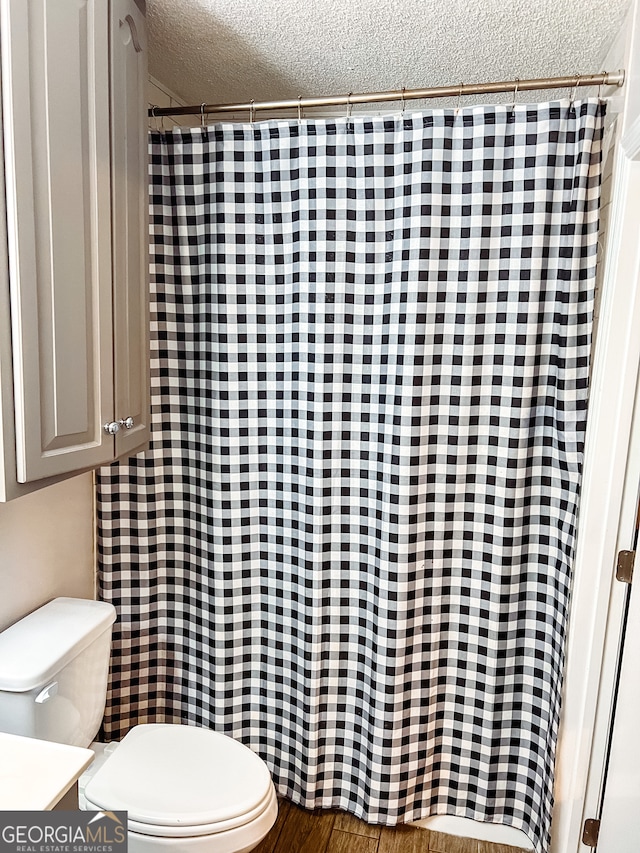 bathroom with hardwood / wood-style floors, a textured ceiling, and toilet