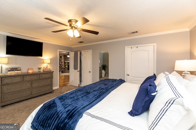 carpeted bedroom with ceiling fan, a textured ceiling, and ornamental molding