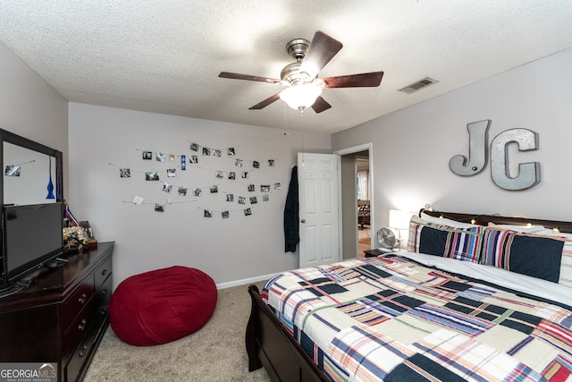 bedroom with ceiling fan, carpet floors, and a textured ceiling