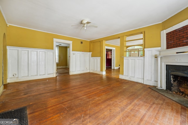 unfurnished living room with hardwood / wood-style floors, ceiling fan, ornamental molding, and a fireplace