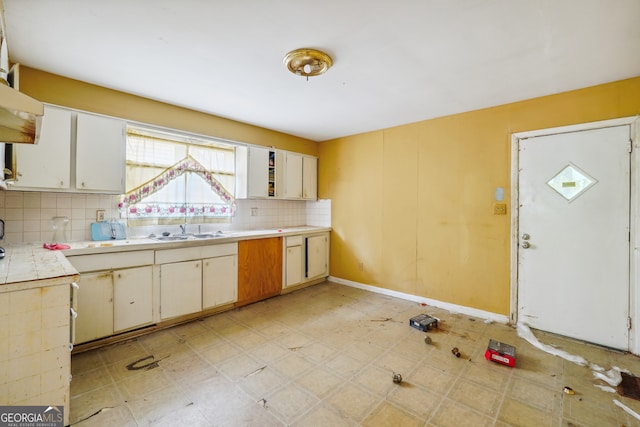 kitchen with tasteful backsplash, white cabinetry, and sink