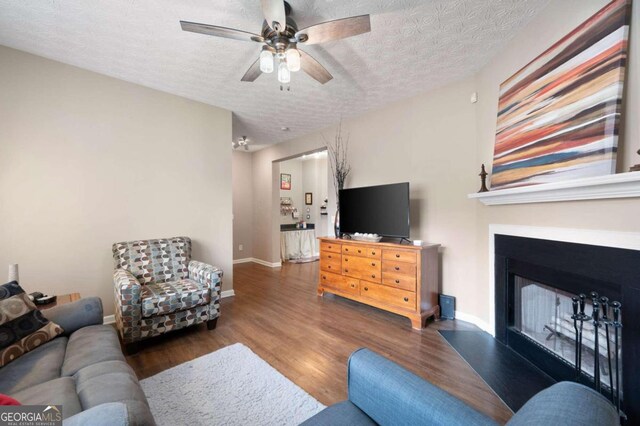 living room featuring ceiling fan, dark hardwood / wood-style flooring, and a textured ceiling