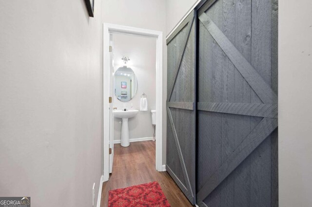 corridor with a barn door and dark hardwood / wood-style flooring