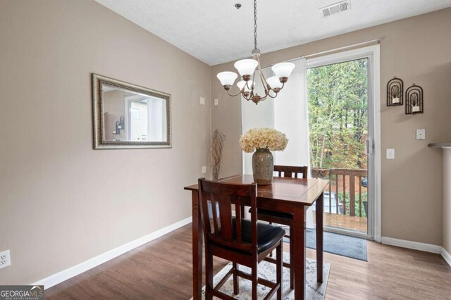 dining room featuring hardwood / wood-style floors, a textured ceiling, and an inviting chandelier