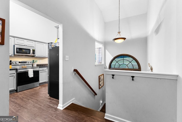 stairway with wood-type flooring and high vaulted ceiling