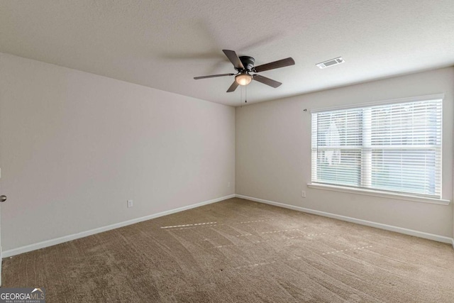 spare room with carpet flooring, ceiling fan, and a textured ceiling