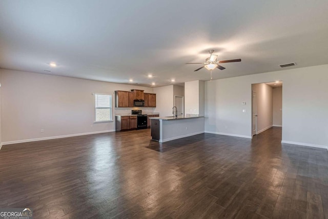 unfurnished living room featuring ceiling fan, dark hardwood / wood-style flooring, and sink