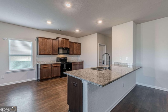 kitchen with black appliances, dark hardwood / wood-style floors, kitchen peninsula, and sink