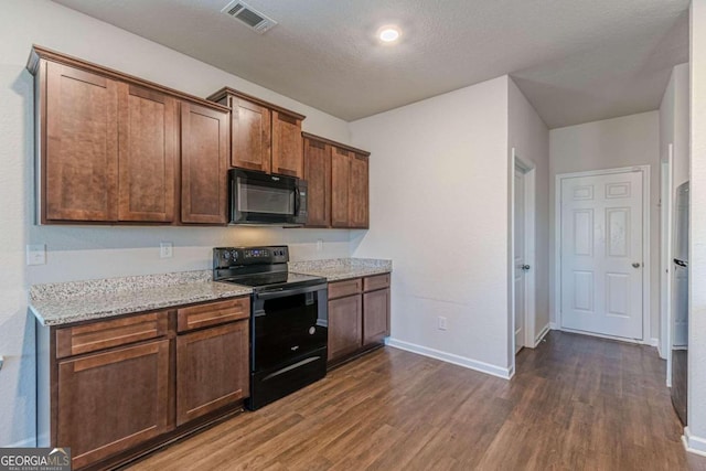 kitchen with light stone countertops, a textured ceiling, dark hardwood / wood-style flooring, and black appliances