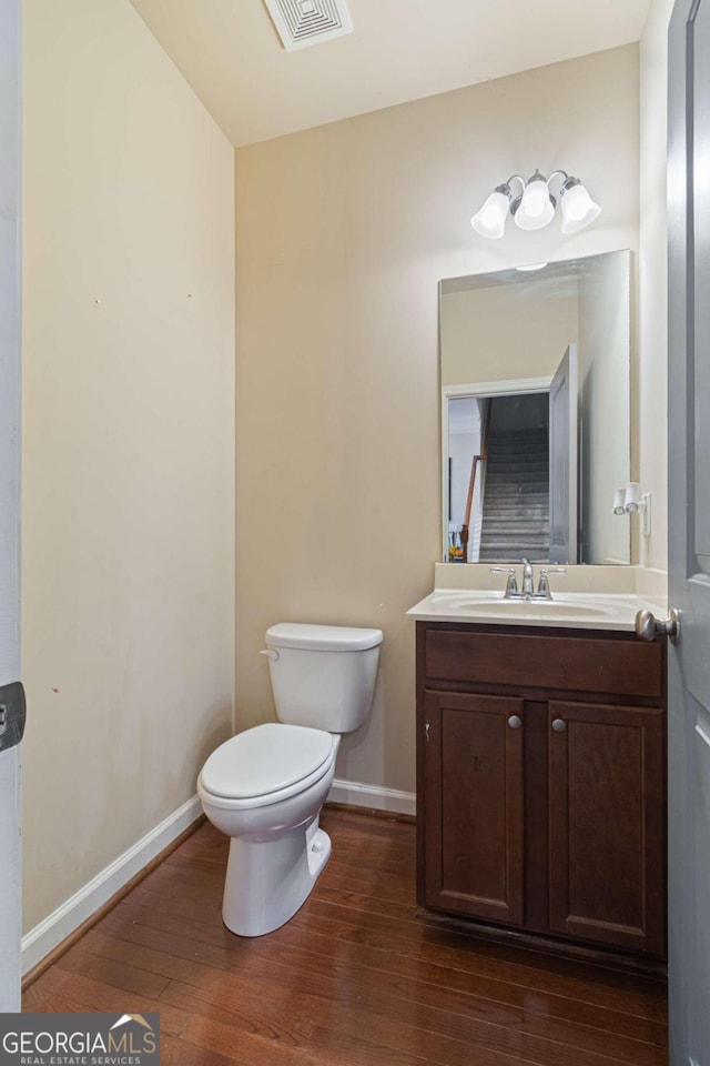 bathroom with toilet, vanity, and hardwood / wood-style flooring