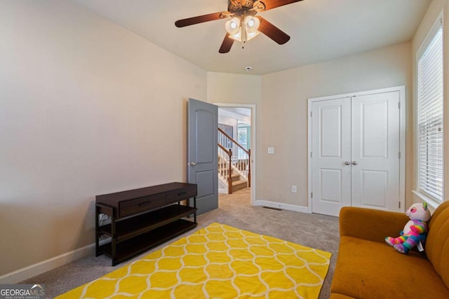 sitting room featuring light colored carpet, ceiling fan, and a healthy amount of sunlight