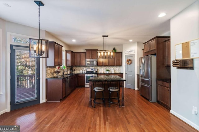 kitchen with a breakfast bar, stainless steel appliances, pendant lighting, a center island, and dark hardwood / wood-style floors