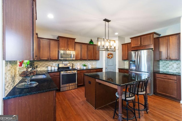 kitchen featuring tasteful backsplash, a kitchen island, dark wood-type flooring, and appliances with stainless steel finishes