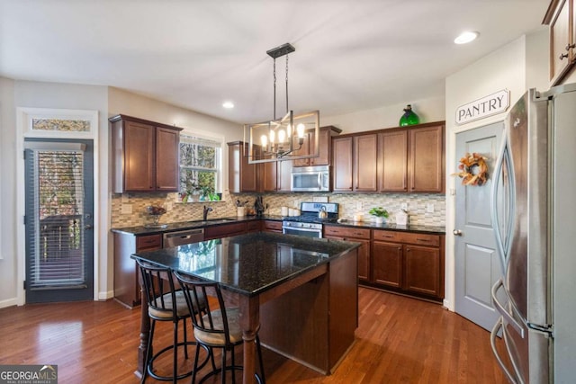 kitchen with pendant lighting, dark hardwood / wood-style flooring, a center island, and stainless steel appliances