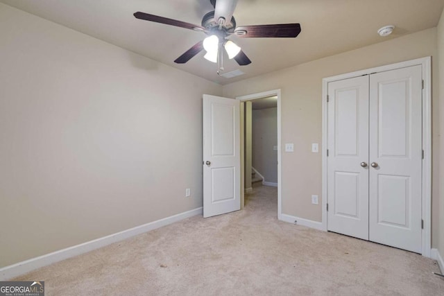 unfurnished bedroom featuring ceiling fan, a closet, and light carpet