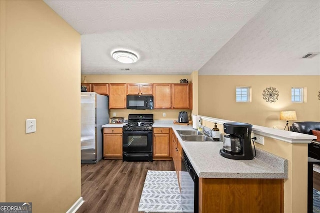 kitchen featuring kitchen peninsula, dark hardwood / wood-style flooring, a textured ceiling, sink, and black appliances