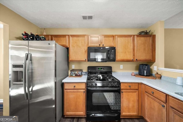 kitchen with black appliances, a textured ceiling, and dark wood-type flooring