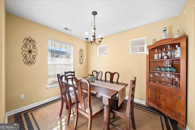 carpeted dining area featuring a textured ceiling and an inviting chandelier