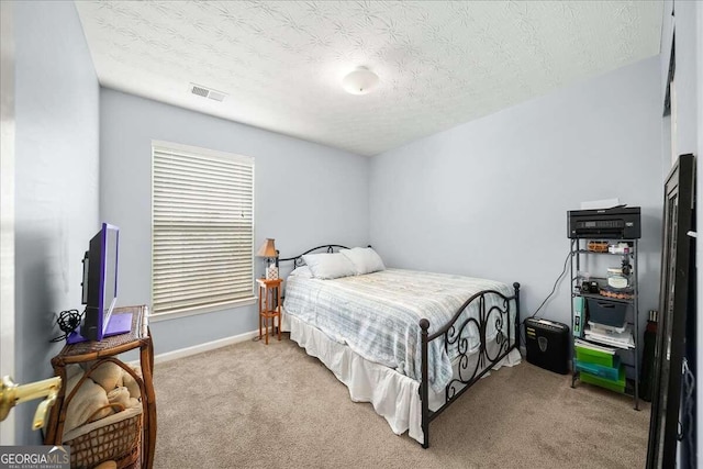 bedroom with a textured ceiling and light carpet