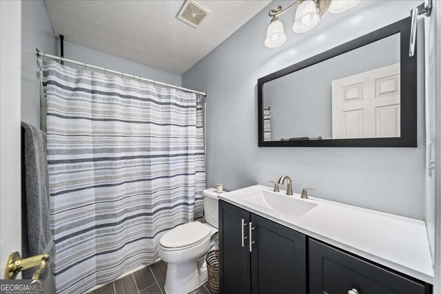 bathroom with a shower with curtain, vanity, a textured ceiling, and toilet