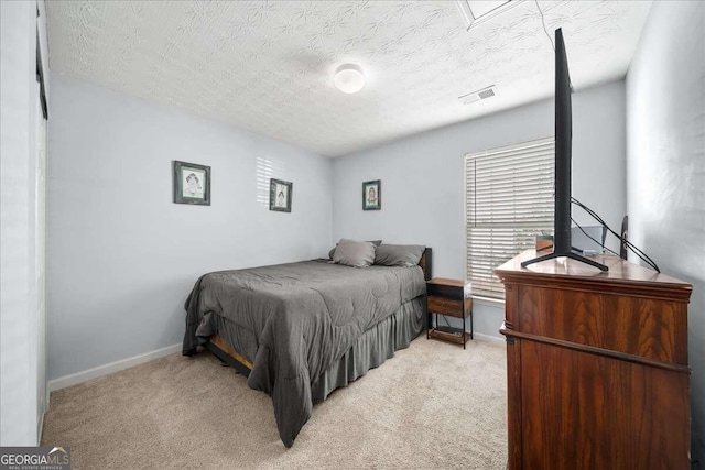 bedroom with a textured ceiling and light colored carpet