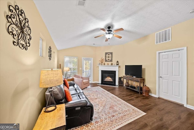 living room with dark hardwood / wood-style flooring, a textured ceiling, vaulted ceiling, and ceiling fan