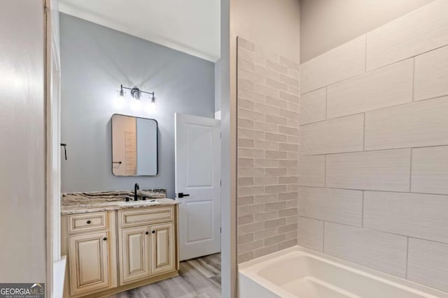 bathroom with wood-type flooring, vanity, and tiled shower / bath