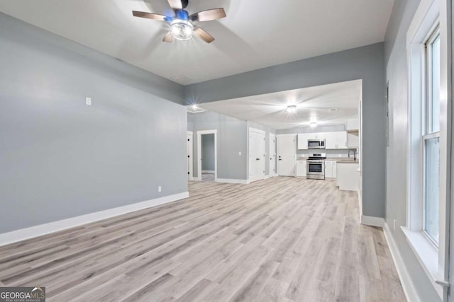 unfurnished living room featuring light hardwood / wood-style flooring, ceiling fan, and sink