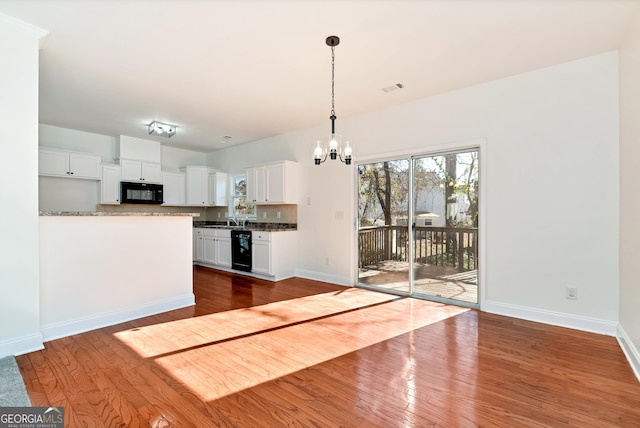 kitchen with light stone counters, dark hardwood / wood-style flooring, backsplash, decorative light fixtures, and white cabinets