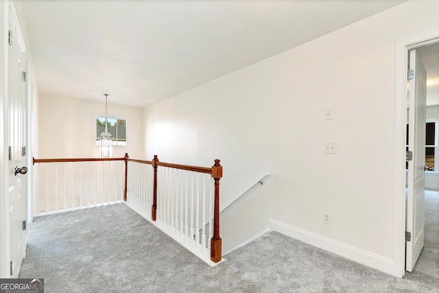 hall featuring light carpet and a notable chandelier