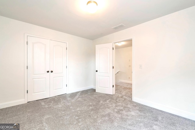 unfurnished bedroom with light carpet and a closet