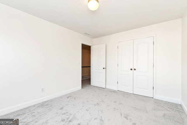 unfurnished bedroom featuring a closet and light colored carpet