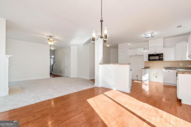 kitchen with decorative backsplash, ceiling fan with notable chandelier, pendant lighting, light hardwood / wood-style floors, and white cabinetry